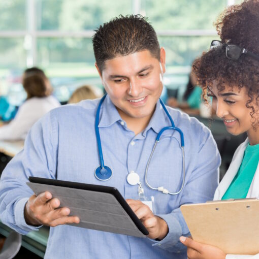 Diverse male and female doctors examine something on digital tablet during medical seminar.